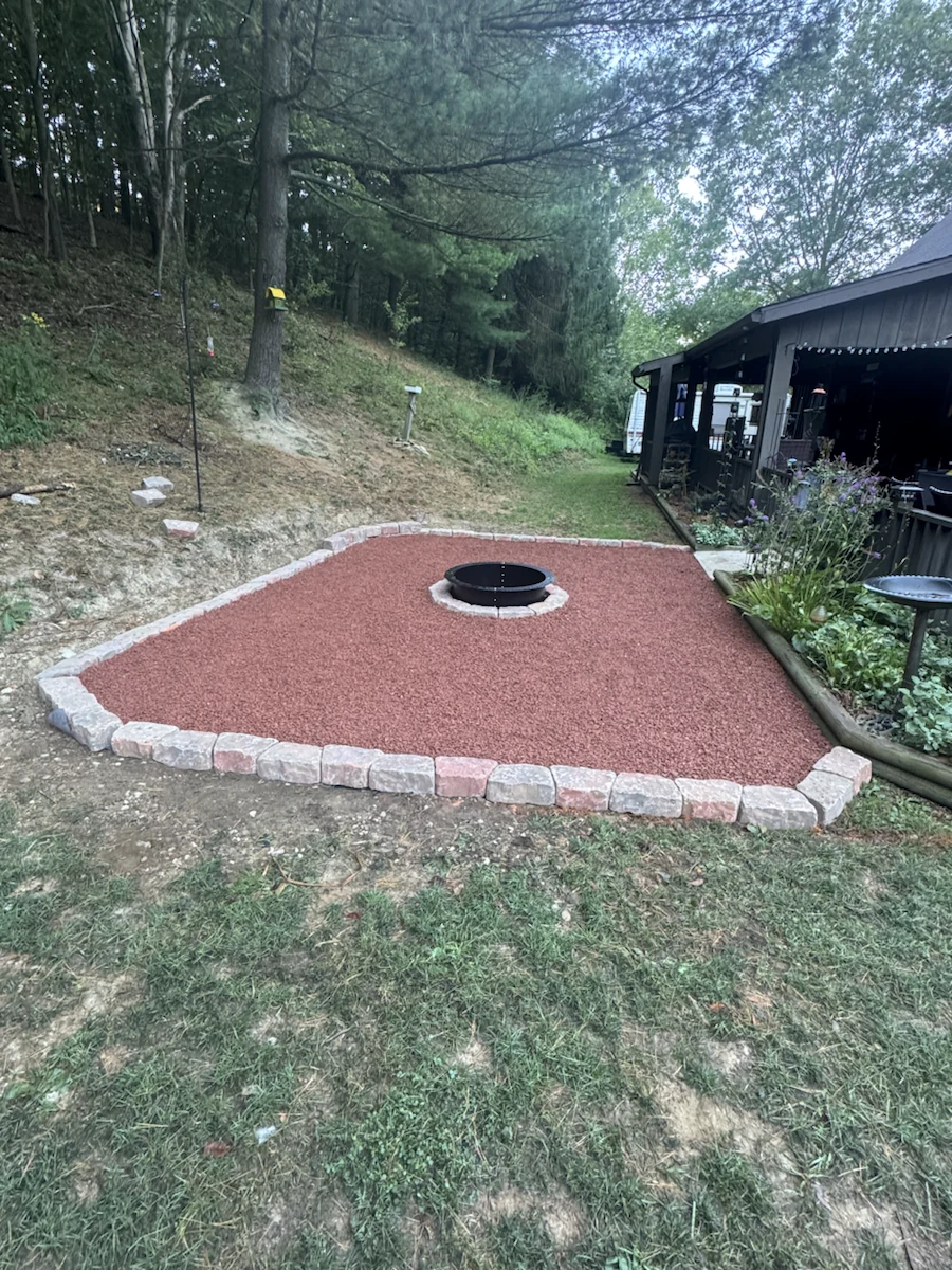 Finished red decorative-stone fire-pit area with a light-colored block border