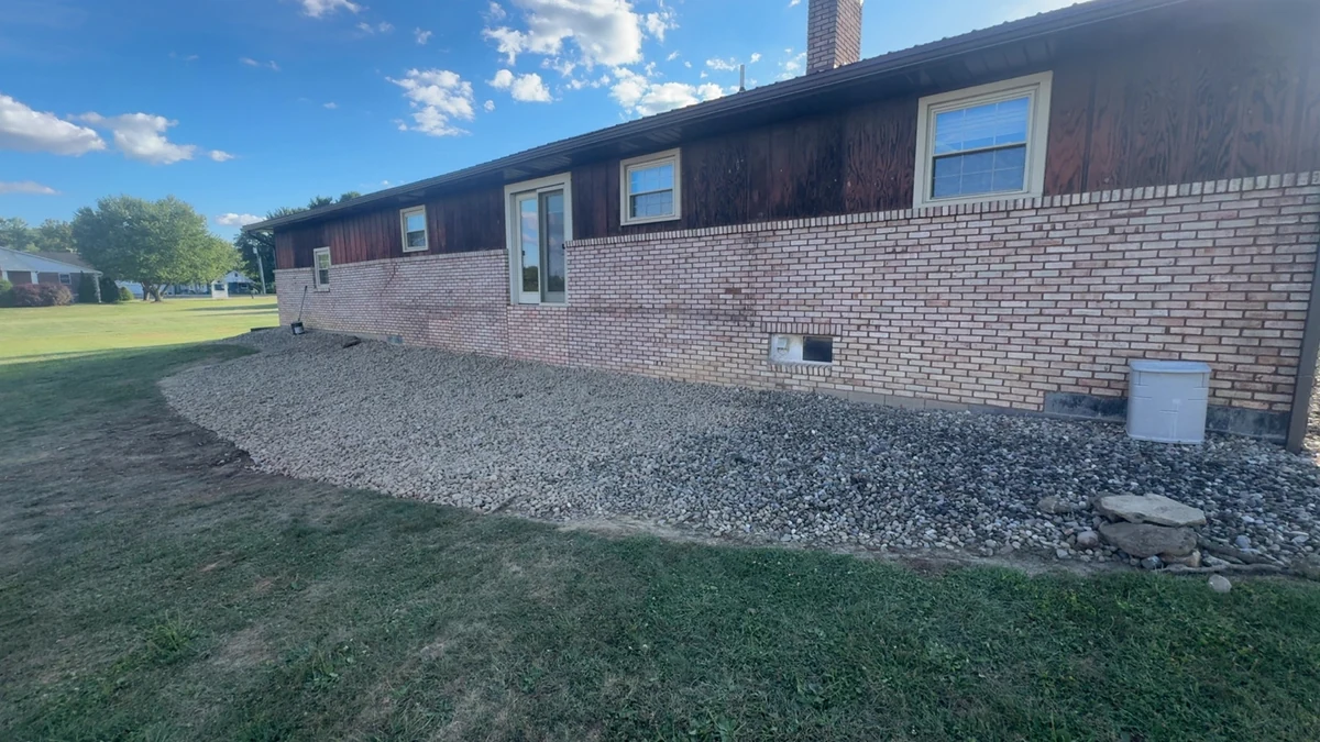 Completed decorative-stone bed beside a brick home